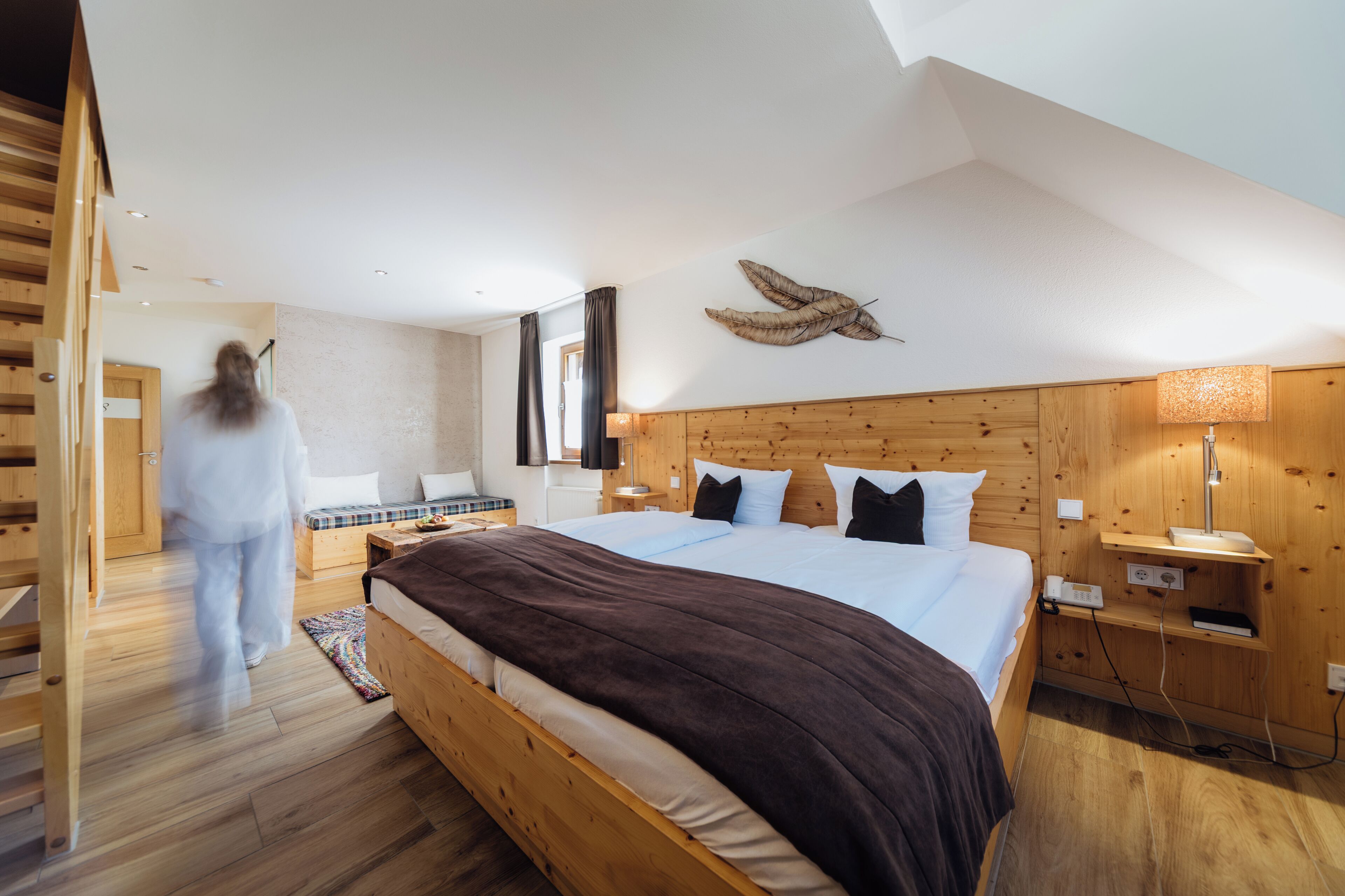 Une chambre à coucher avec un lit en bois, une table de chevet, une lampe et une grande fenêtre.