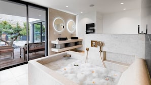 Un baño moderno con una bañera grande, dos lavamanos y una ducha.