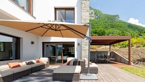A modern outdoor living area with a sofa, chairs, and a table under a large umbrella.