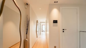 A hallway with wooden flooring, a white door, and a wall-mounted security camera.