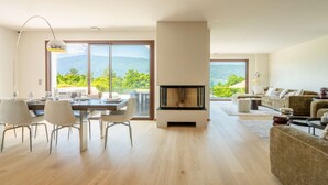 A modern living room with a fireplace, a dining area with a table and chairs, and a sofa.