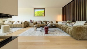 A modern living room with a sectional sofa, a coffee table, and a large window with a view of greenery.