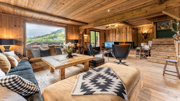 Een gezellig houten interieur met een bank, bijzettafeltje en open haard.