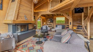 A cozy cabin interior with a fireplace, seating area, and a staircase.