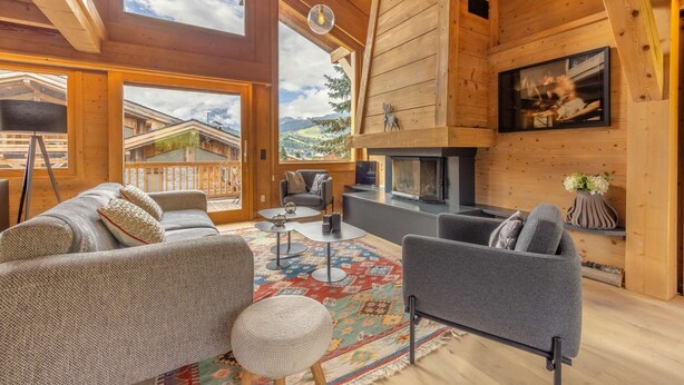 A spacious living area with a fireplace, comfortable seating, and large windows offering a view of the surrounding landscape.