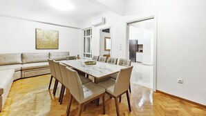 Et moderne spiseområde med et marmorbord, læderstole, en sofa og et stort vindue.