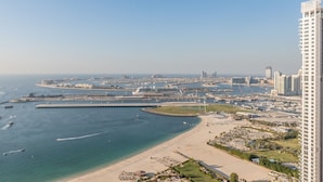 Un paysage urbain côtier avec une plage, un port de plaisance et des immeubles de grande hauteur.