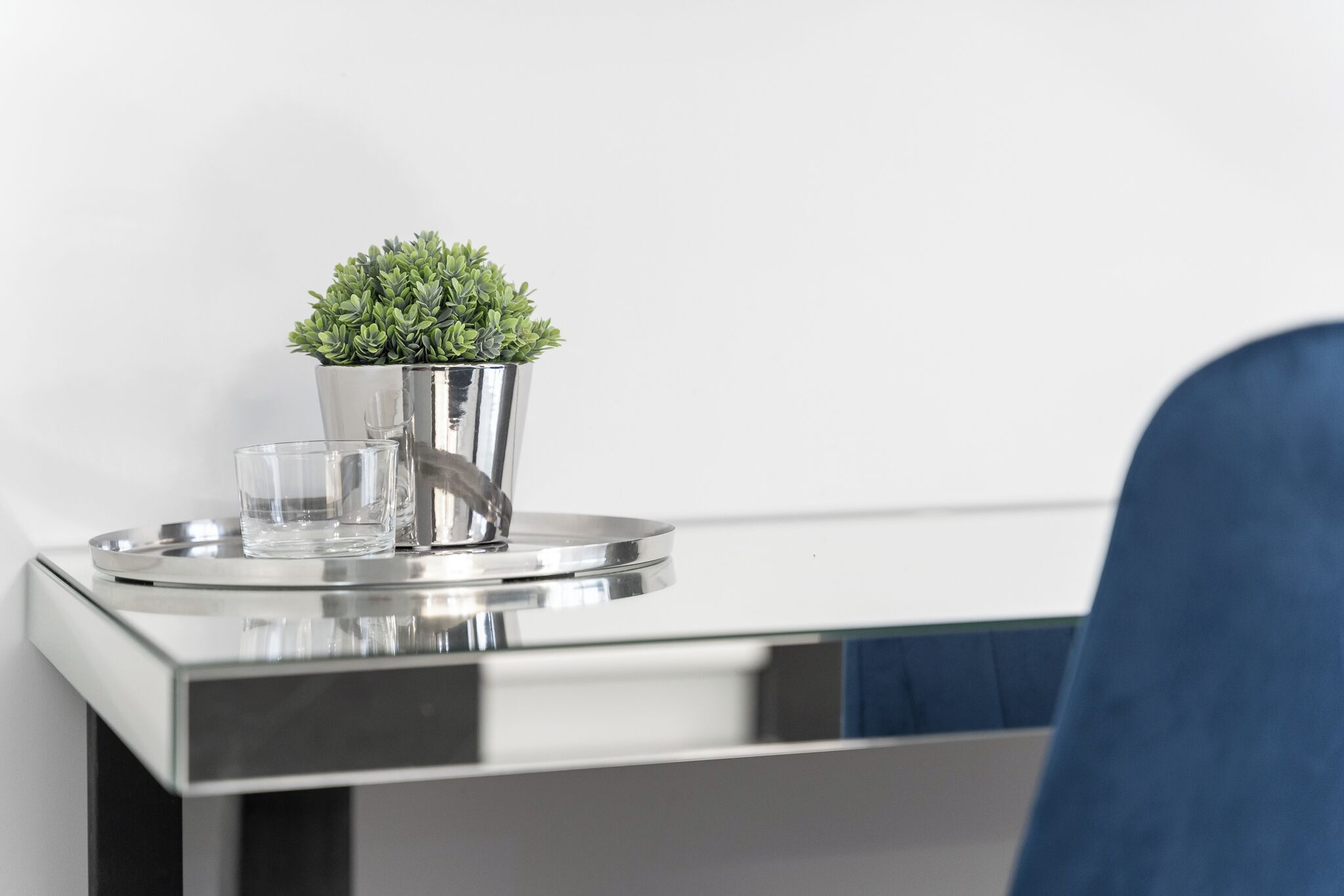 Una mesa metálica moderna con una pequeña planta en maceta y dos vasos.