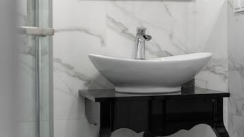 A bathroom with a white marble sink, a black vanity, and a glass shower enclosure.