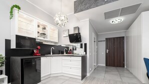 Een moderne keuken met witte kastjes, een zwarte vaatwasser en een inbouwmagnetron.