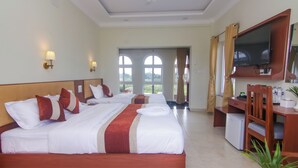 A hotel room with two beds, a desk, a TV, and a view of the outdoors. - Hotel Yatra Sauraha (Sauraha)