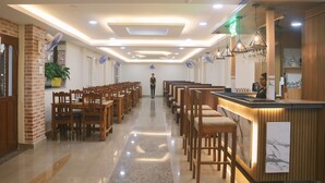 A hotel lobby with wooden chairs arranged in rows, a reception desk, and a potted plant. - Hotel Yatra Sauraha (Sauraha)