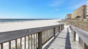 A wooden boardwalk leading to a beach with a clear view of the ocean and a hotel in the background. - Seaside Beach 5417 | Beachfront Condo w/ Pool, Sauna & Balcony Gulf (Orange Beach)