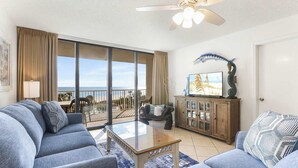 A living room with a sofa, a coffee table, and a television on a wooden cabinet. - Seaside Beach 5417 | Beachfront Condo w/ Pool, Sauna & Balcony Gulf (Orange Beach)
