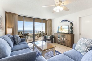 A living room with a sofa, a coffee table, and a television on a wooden cabinet. - Seaside Beach 5417 | Beachfront Condo w/ Pool, Sauna & Balcony Gulf (Orange Beach)