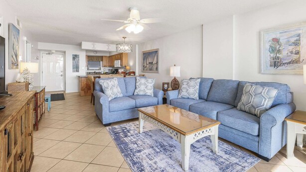 A living room with a sofa set, a coffee table, and a kitchen in the background. - Seaside Beach 5417 | Beachfront Condo w/ Pool, Sauna & Balcony Gulf (Orange Beach)
