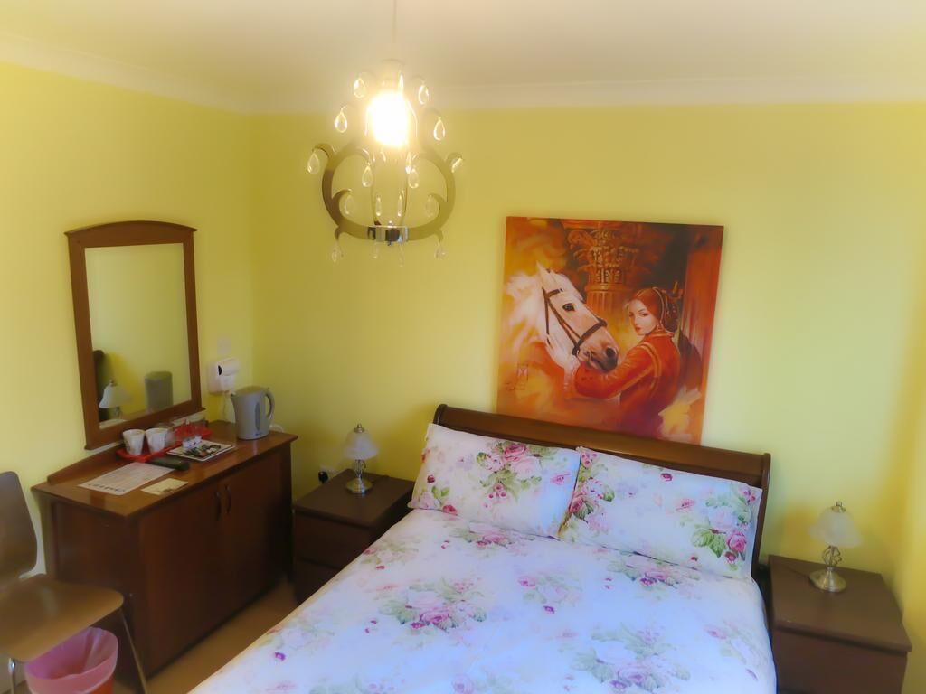 Ein Schlafzimmer mit Bett, Schreibtisch, Stuhl, Nachttisch, Lampe und einem Bild an der Wand.
