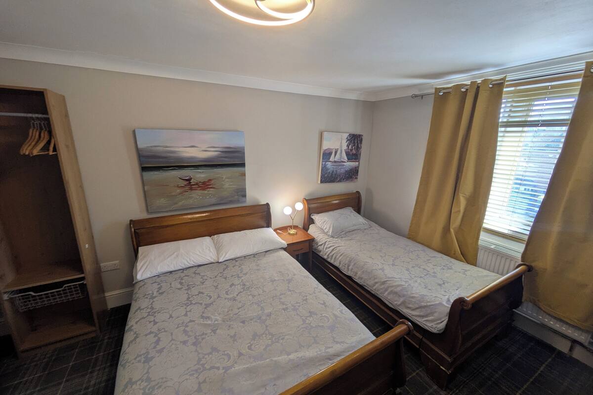 Une chambre avec deux lits, une armoire et des œuvres d’art accrochées au mur.