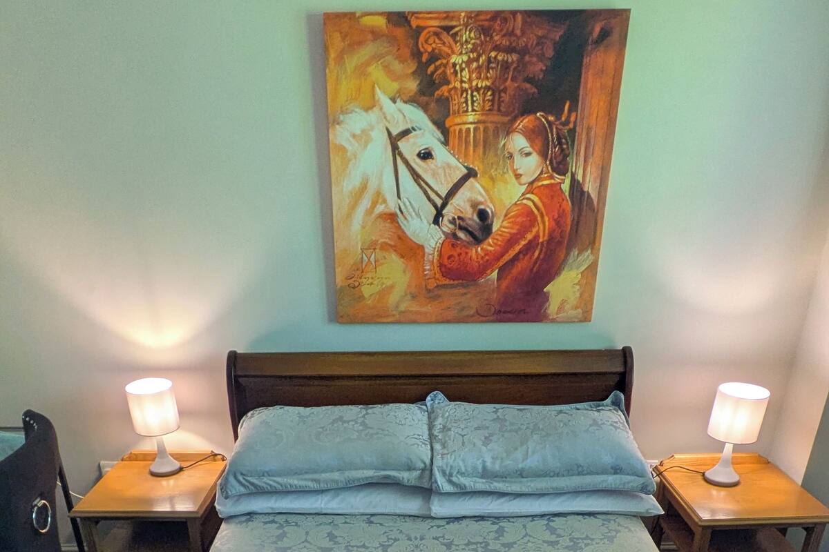 Une chambre d’hôtel avec un grand lit, deux tables de chevet avec des lampes, une chaise et un tableau au mur.