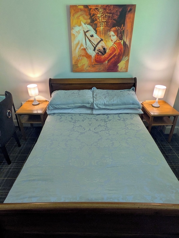 A hotel room with a large bed, two bedside tables with lamps, a chair, and a painting on the wall. - The Godalming Hotel (Godalming)