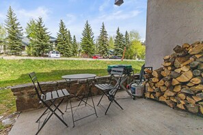 An outdoor patio with a table and chairs, a stack of firewood, and a propane tank. - Steamboat Mountain Condo
ski in/ski out, Great biking/amenities/location/access (Steamboat Springs)