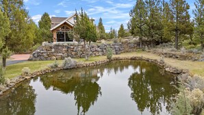 Una casa con un muro de piedra y un estanque al frente.