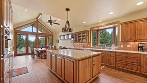 Una cocina amplia con armarios de madera, una isla grande y un comedor con vista al exterior.