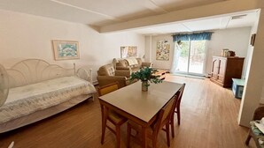 En kompakt opholdsstue med sofa, spisebord og et lille tekøkken.