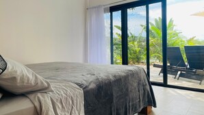A bedroom with a bed, a view of an outdoor area with chairs and plants. - Charming 3-bedroom villa in fabulous Puerto Carrillo with WiFi, AC (Puerto Carrillo)