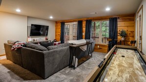 A cozy living room with a sofa, a coffee table, a television, and a shuffleboard table. - Comfort and Luxury at its best, Hot Tub 1 Dog. New Property (Blairsville)