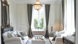 A living room with a chandelier, two sofas, a coffee table, and a window with curtains.