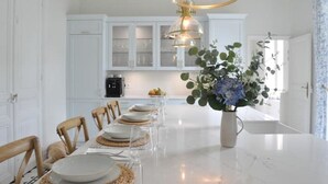 A kitchen with white cabinets, a marble countertop, and a dining table set for six.