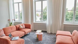 A room with two sofas, a small table, and large windows with curtains. - Luxurious townhouse in AAA location with nearby parking. (Brugge)