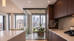 A modern kitchen with a large island, a dining area with a view, and a cityscape visible through large windows.