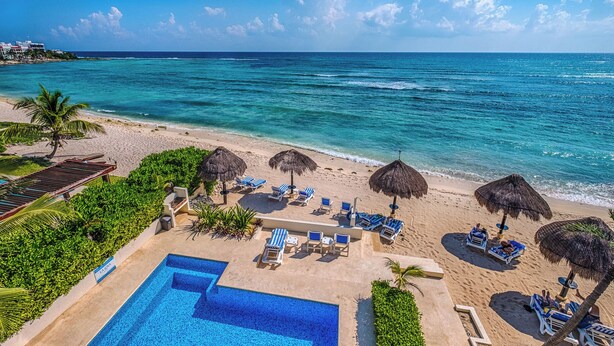 A resort pool area with a clear view of the ocean, lounge chairs, and a swimming pool. - Newly Renovated Bright and Relaxing Studio (Akumal)