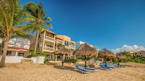 A beachfront hotel with multiple balconies, thatched umbrellas, and blue lounge chairs. - Newly Renovated Bright and Relaxing Studio (Akumal)