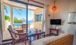 A room with a view of a pool, a TV, and a dining area with chairs and a table.
