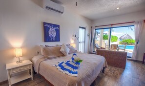 A bedroom with a bed, a nightstand, a lamp, a painting, and a view of the pool outside.
