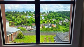 A view through a window of a residential area with houses, greenery, and a clear sky. - Hotel Eifeler Hof Kyllburg (Kyllburg)