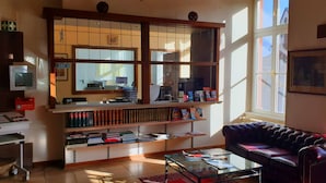 A well-lit living room with a leather sofa, a glass coffee table, and a large window providing natural light. - Hotel Eifeler Hof Kyllburg (Kyllburg)