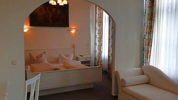 Un dormitorio con cama, mesita de noche, silla y un cuadro en la pared.