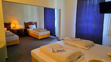 A hotel room with two beds, a desk, a lamp, and a television.