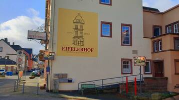 Een gebouw met een groot bord voor Hotel & Restaurants Eifelerhof, met een afbeelding van een historisch pand.