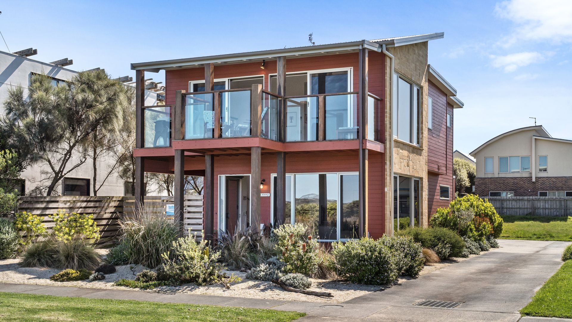 A modern two-story house with large glass windows and a flat roof.