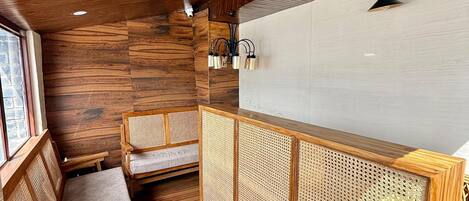 A wooden interior with a bench, a woven partition, and a white wall.