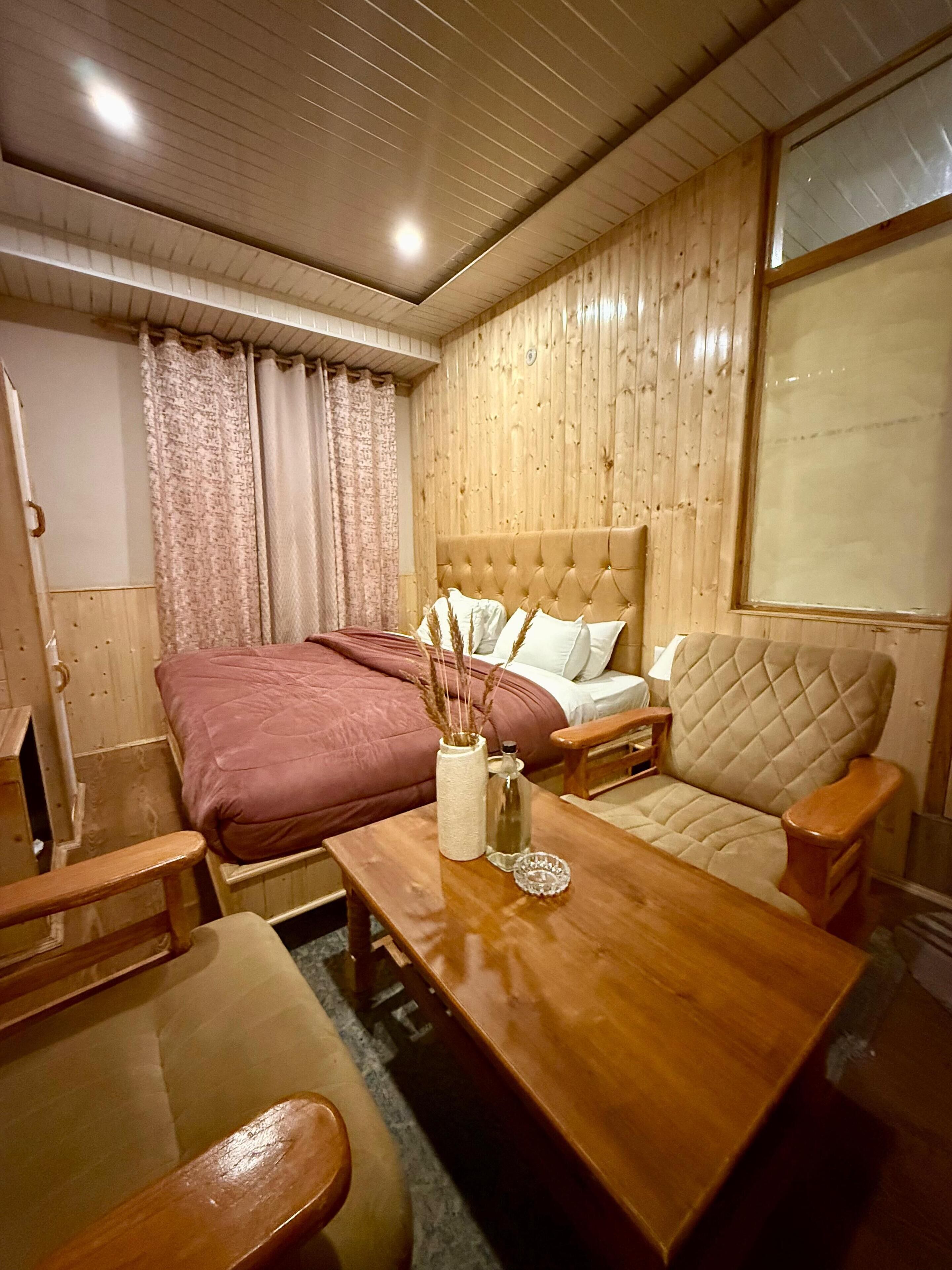 A cozy room with a bed, a sofa, a wooden table, and a window with curtains.