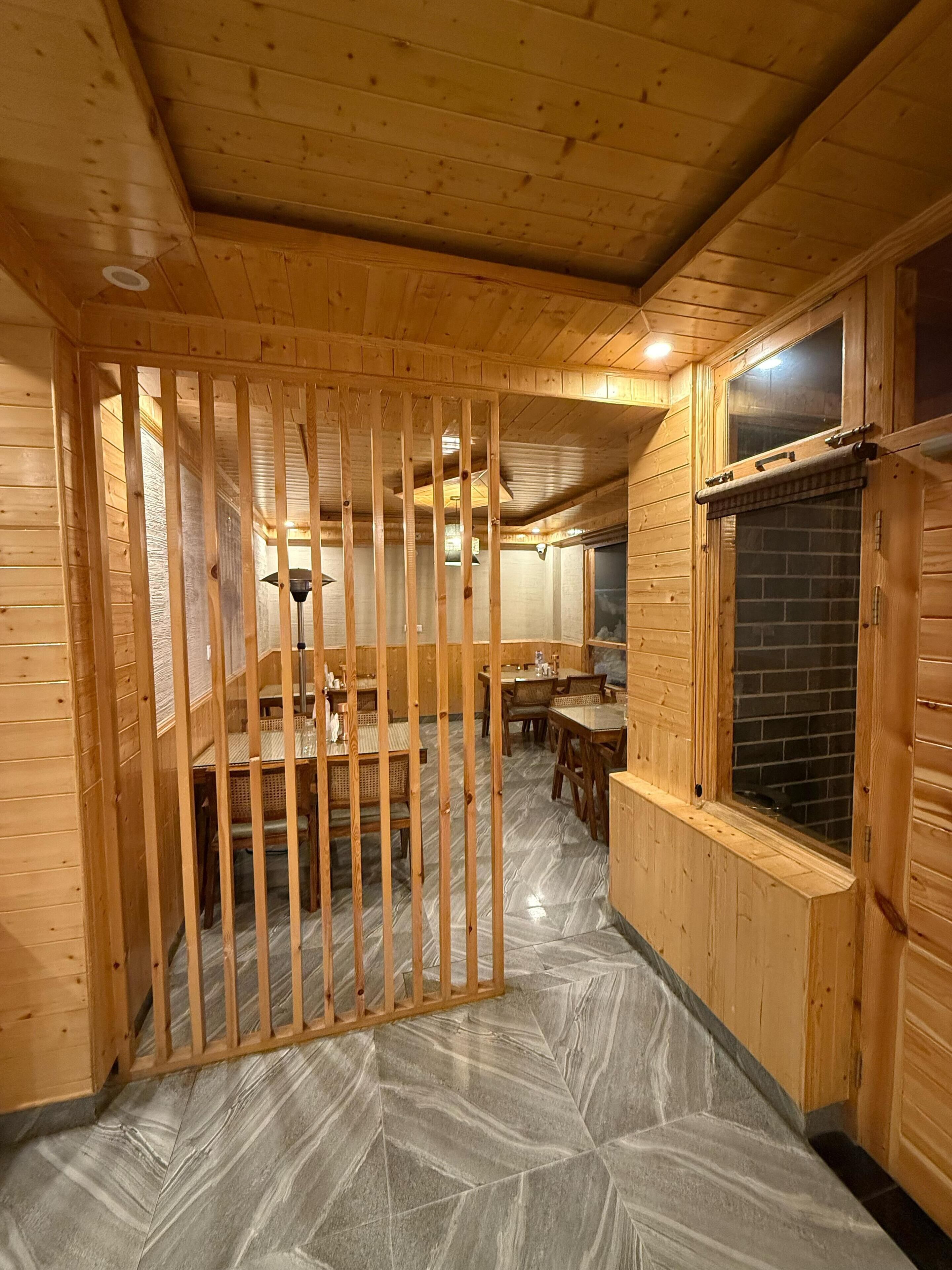 Un intérieur en bois comprenant un coin repas, une cheminée et une vue par une fenêtre.