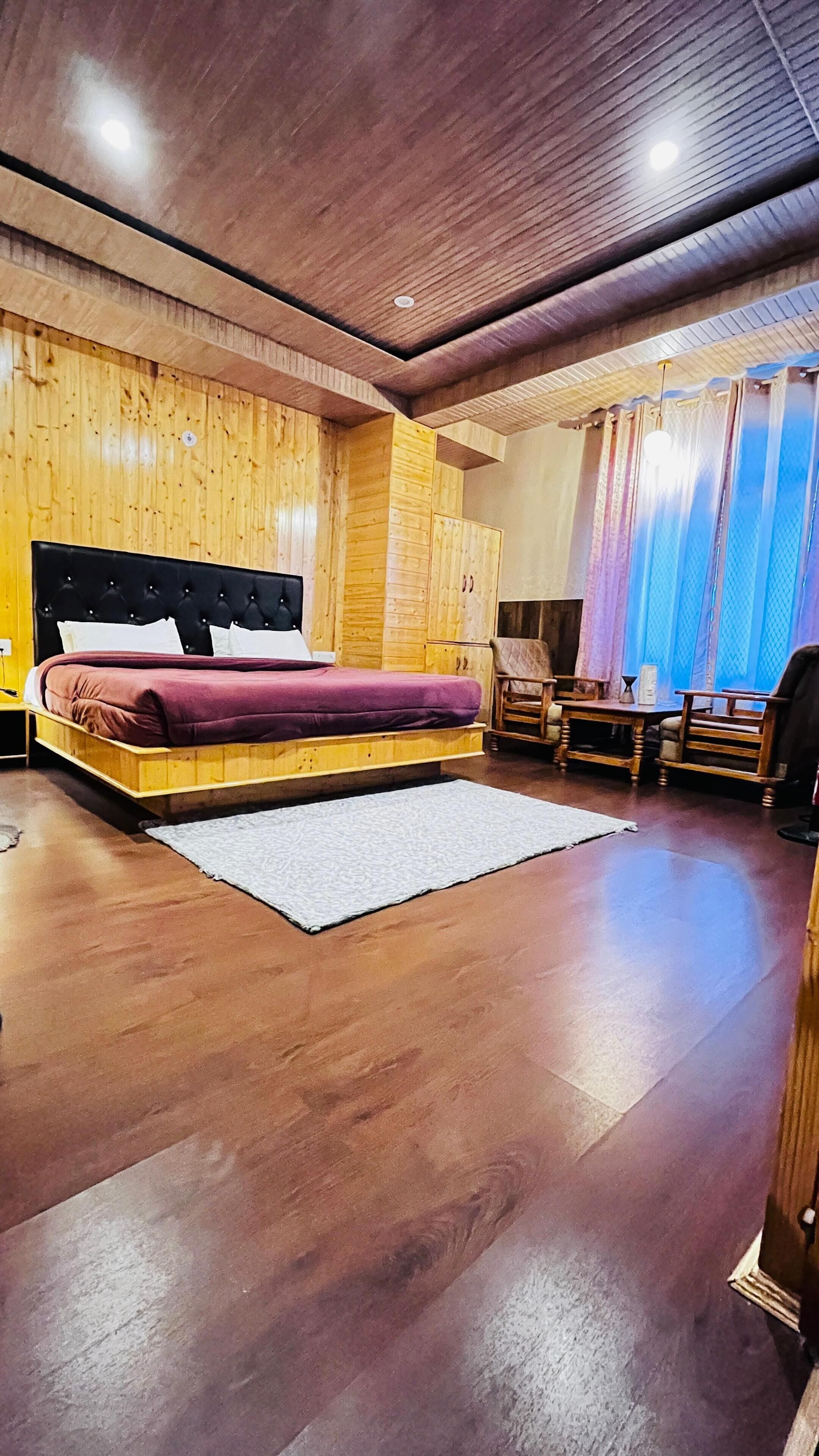 A wooden bedroom with a bed, a chair, a nightstand, and a window with curtains.