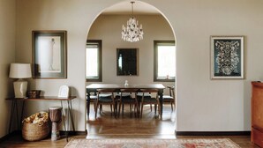 Un coin repas avec une table en bois, des chaises, un lustre et des œuvres d’art encadrées accrochées aux murs.