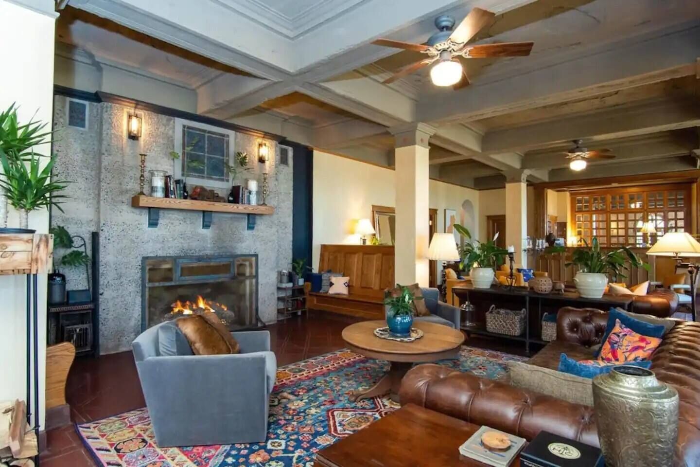 A spacious living room with a fireplace, leather sofas, a coffee table, and a large rug.